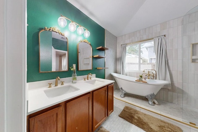 bathroom with double vanity, vaulted ceiling, a freestanding bath, and a sink