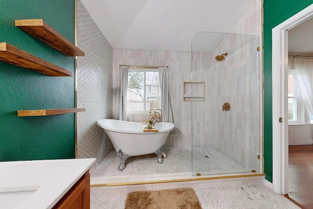 full bathroom with lofted ceiling, a soaking tub, a tile shower, and vanity