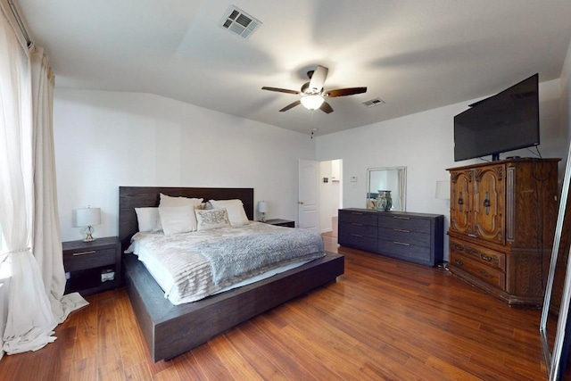 bedroom with ceiling fan, visible vents, wood finished floors, and vaulted ceiling