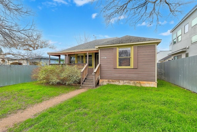 back of property featuring a fenced backyard, a shingled roof, and a lawn