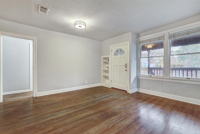 foyer featuring baseboards, a textured ceiling, visible vents, and dark wood-style flooring