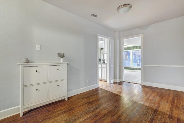 unfurnished room with wood finished floors, visible vents, and baseboards