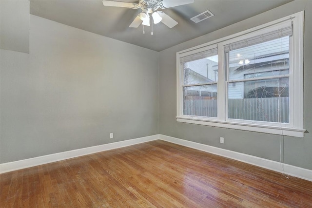 unfurnished room featuring a ceiling fan, wood finished floors, visible vents, and baseboards