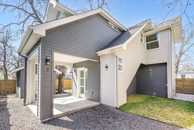 back of house featuring a shingled roof, fence, and a patio