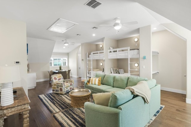 living room featuring baseboards, visible vents, ceiling fan, and wood finished floors