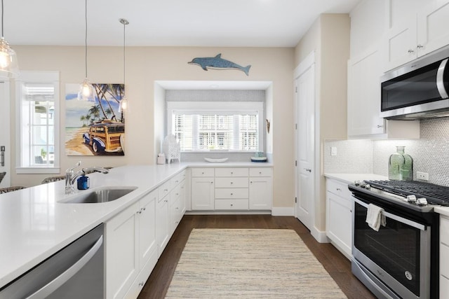 kitchen with a sink, white cabinetry, light countertops, appliances with stainless steel finishes, and decorative light fixtures