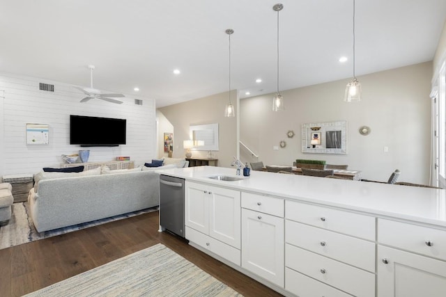 kitchen with a sink, white cabinetry, open floor plan, hanging light fixtures, and light countertops