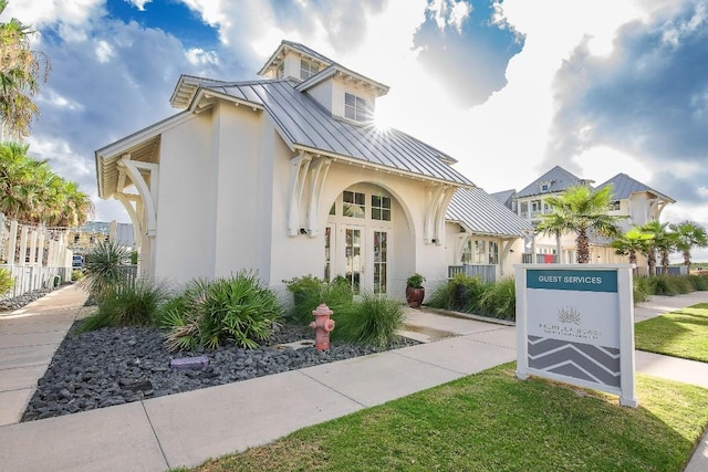 view of front of property featuring metal roof, a standing seam roof, and stucco siding