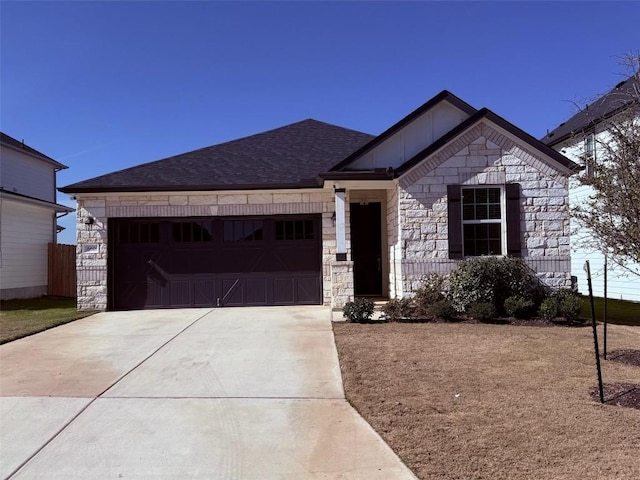 view of front facade with stone siding, a shingled roof, an attached garage, and driveway