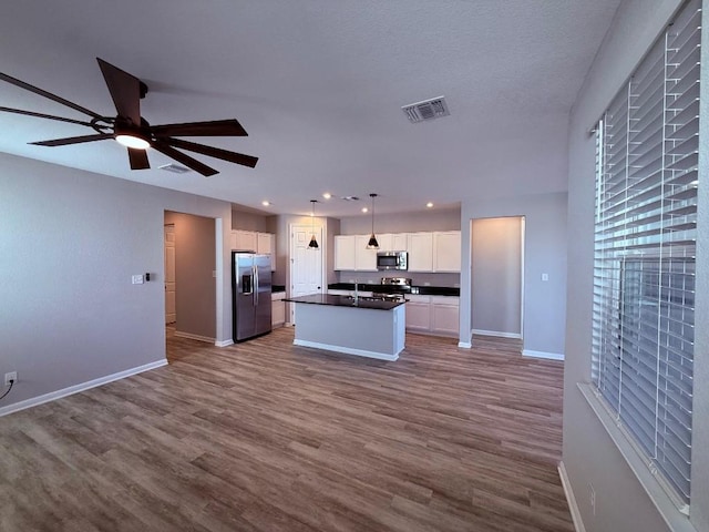 kitchen featuring white cabinetry, visible vents, appliances with stainless steel finishes, a center island, and pendant lighting