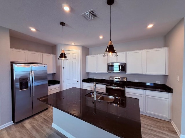 kitchen with visible vents, decorative light fixtures, stainless steel appliances, white cabinetry, and a sink