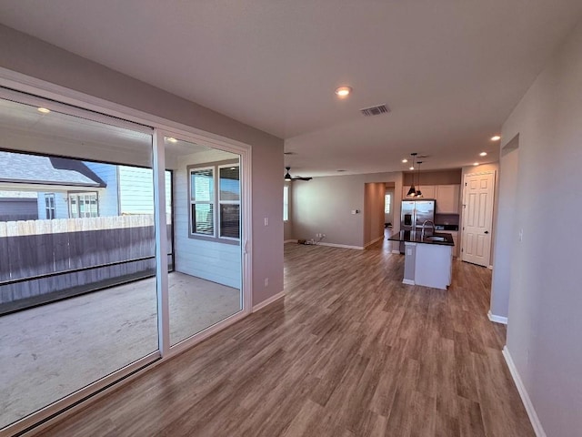 unfurnished living room with recessed lighting, a sink, visible vents, baseboards, and light wood-style floors