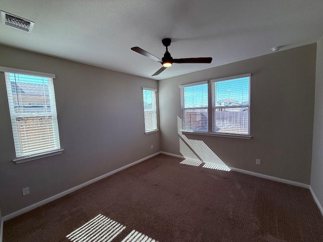 spare room featuring carpet floors, baseboards, visible vents, and a ceiling fan