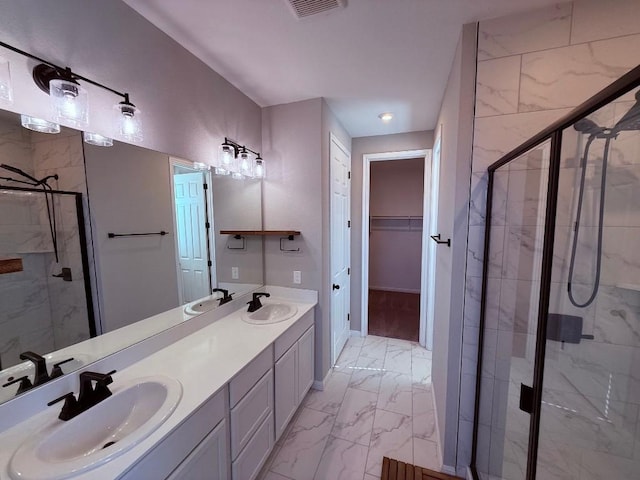 bathroom with marble finish floor, a sink, and a stall shower