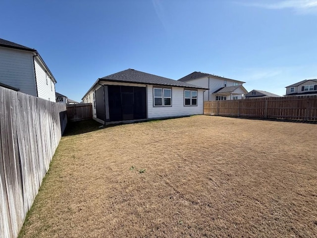 back of house with a fenced backyard and a yard