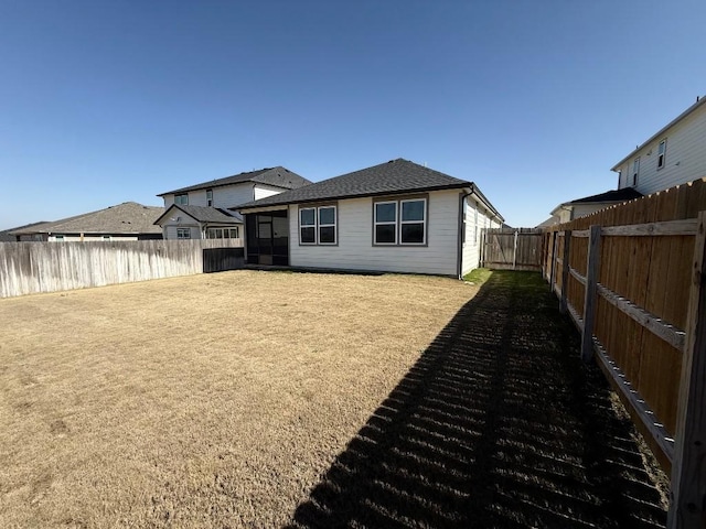 rear view of property featuring a fenced backyard and roof with shingles