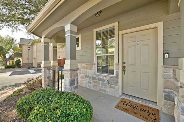 entrance to property featuring covered porch and stone siding