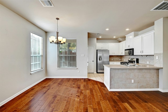 11000 Anderson Mill Rd Unit 52, Austin, TX 78750 - kitchen with stainless steel appliances, hardwood / wood-style flooring, a chandelier, light countertops, and backsplash