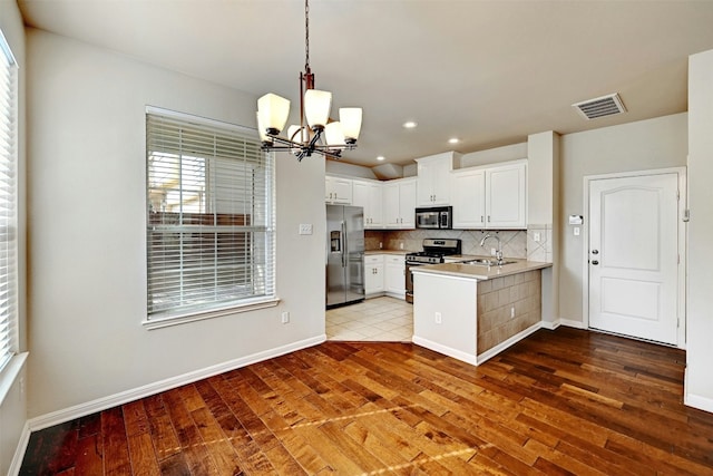 11000 Anderson Mill Rd Unit 52, Austin, TX 78750 - kitchen with stainless steel appliances, a chandelier, hardwood / wood-style floors, a peninsula, and decorative backsplash