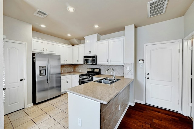 11000 Anderson Mill Rd Unit 52, Austin, TX 78750 - kitchen featuring appliances with stainless steel finishes, a sink, a peninsula, white cabinets, and tasteful backsplash