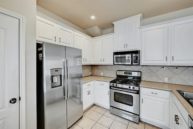 kitchen featuring light tile patterned floors, tasteful backsplash, light countertops, appliances with stainless steel finishes, and white cabinetry