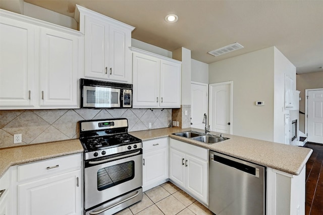 kitchen featuring stainless steel appliances, white cabinets, a sink, and visible vents