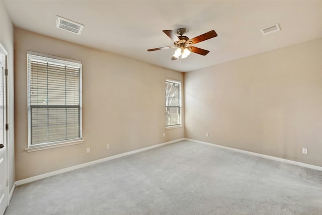 empty room featuring baseboards, a ceiling fan, visible vents, and light colored carpet