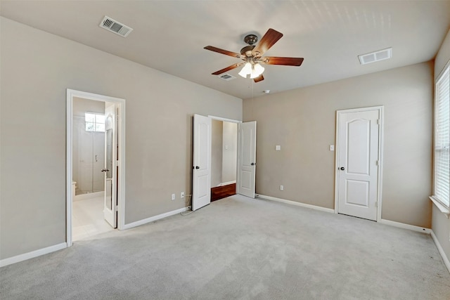 unfurnished bedroom featuring light colored carpet, visible vents, baseboards, and ensuite bathroom