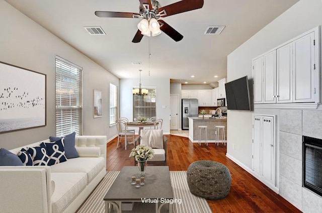 living room featuring a fireplace, visible vents, dark wood-style flooring, and recessed lighting