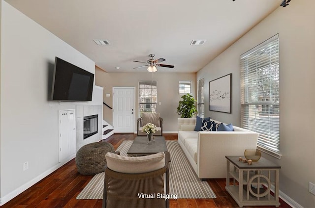 living area with baseboards, visible vents, dark wood-type flooring, and a tile fireplace