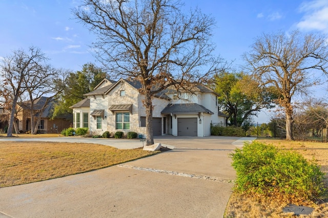 view of front facade featuring driveway, stone siding, an attached garage, and a front yard