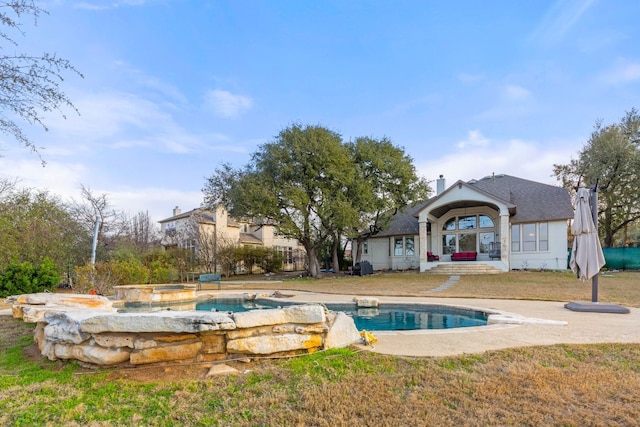 view of swimming pool with a lawn and an in ground hot tub