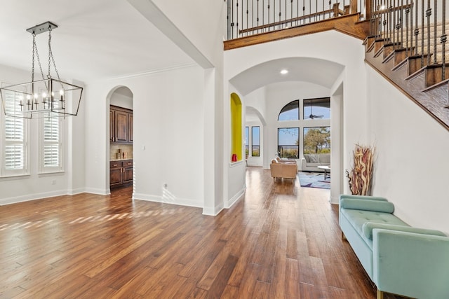 foyer featuring a towering ceiling, baseboards, and hardwood / wood-style floors