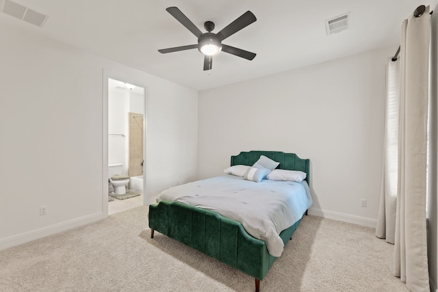 carpeted bedroom featuring a ceiling fan, ensuite bath, visible vents, and baseboards