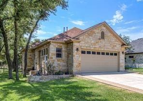 view of front of home with a garage, concrete driveway, stone siding, and a front yard