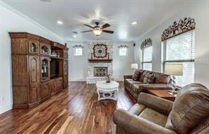 living room featuring crown molding, dark wood-style flooring, a fireplace, and a healthy amount of sunlight