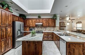 kitchen featuring a kitchen island, a peninsula, stainless steel appliances, under cabinet range hood, and a sink