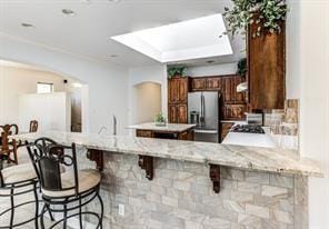 kitchen featuring a breakfast bar area, a peninsula, and stainless steel fridge with ice dispenser