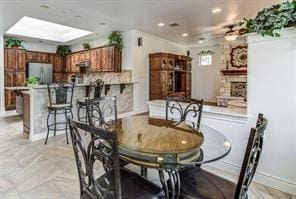 dining space featuring a skylight, a fireplace, and recessed lighting