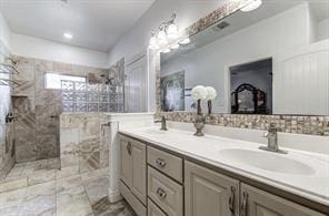 bathroom featuring double vanity, walk in shower, and a sink