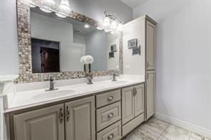 bathroom featuring double vanity, tile patterned floors, a sink, and baseboards