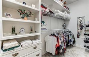 walk in closet featuring marble finish floor