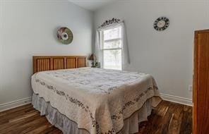 bedroom with baseboards and dark wood-style flooring