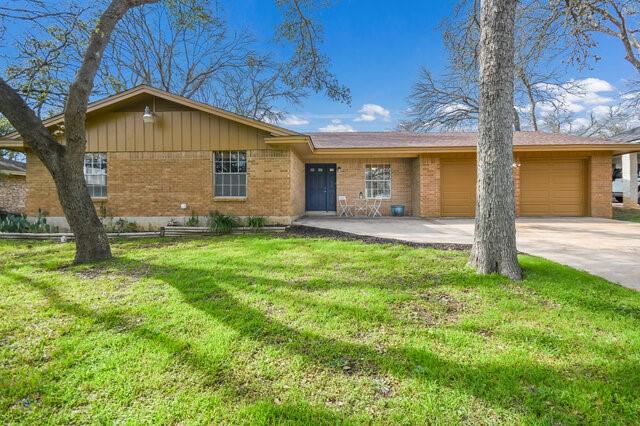 single story home featuring driveway, a garage, a front lawn, and brick siding