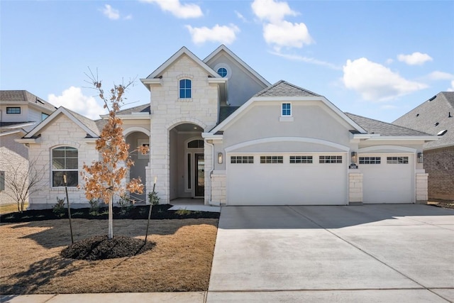 view of front of house with an attached garage, stone siding, concrete driveway, and stucco siding