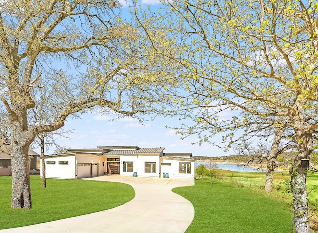 view of front of property with a water view, driveway, a front lawn, and stucco siding