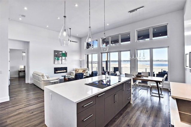 kitchen with black electric stovetop, a water view, open floor plan, a kitchen island, and modern cabinets