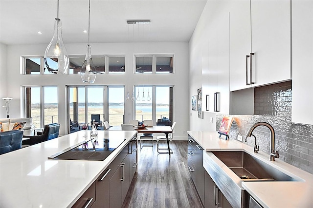 kitchen with light countertops, hanging light fixtures, a water view, and a sink