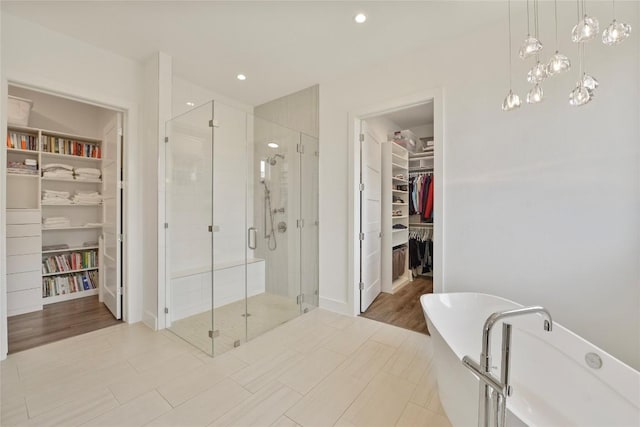 full bathroom with a spacious closet, a stall shower, a freestanding tub, and recessed lighting