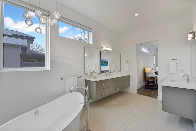 bathroom with a freestanding tub, baseboards, two vanities, and a sink